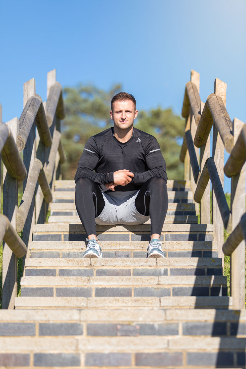 The coach is posing while sitting at the stairs.
