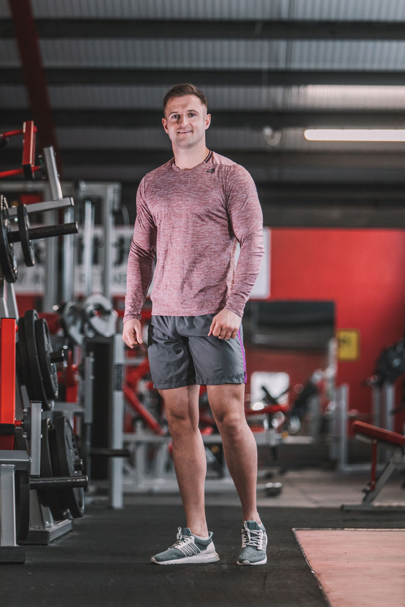 The coach is posing at the gym.